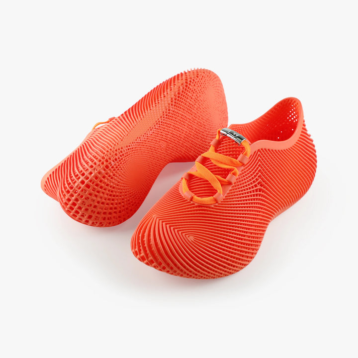 Pair of lightweight 3D printed shoes in bright orange