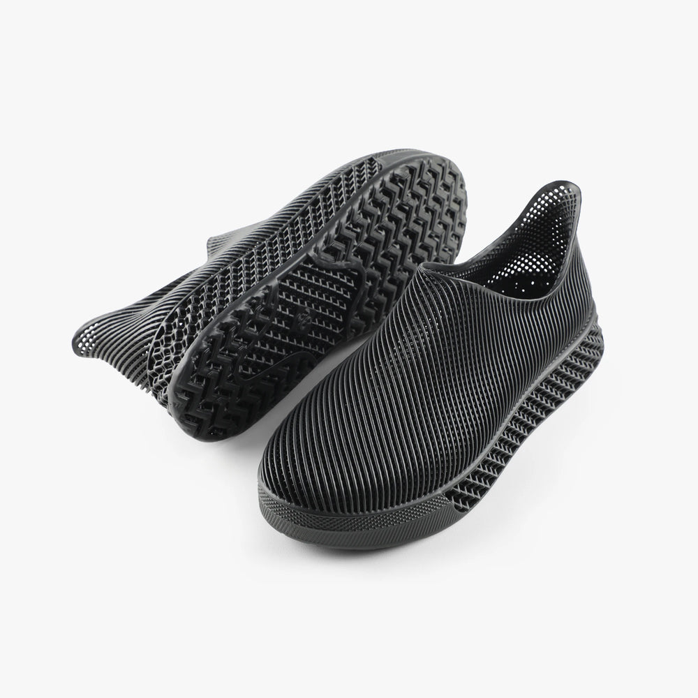 Black 3d printed shoes with textured sole on a white background
