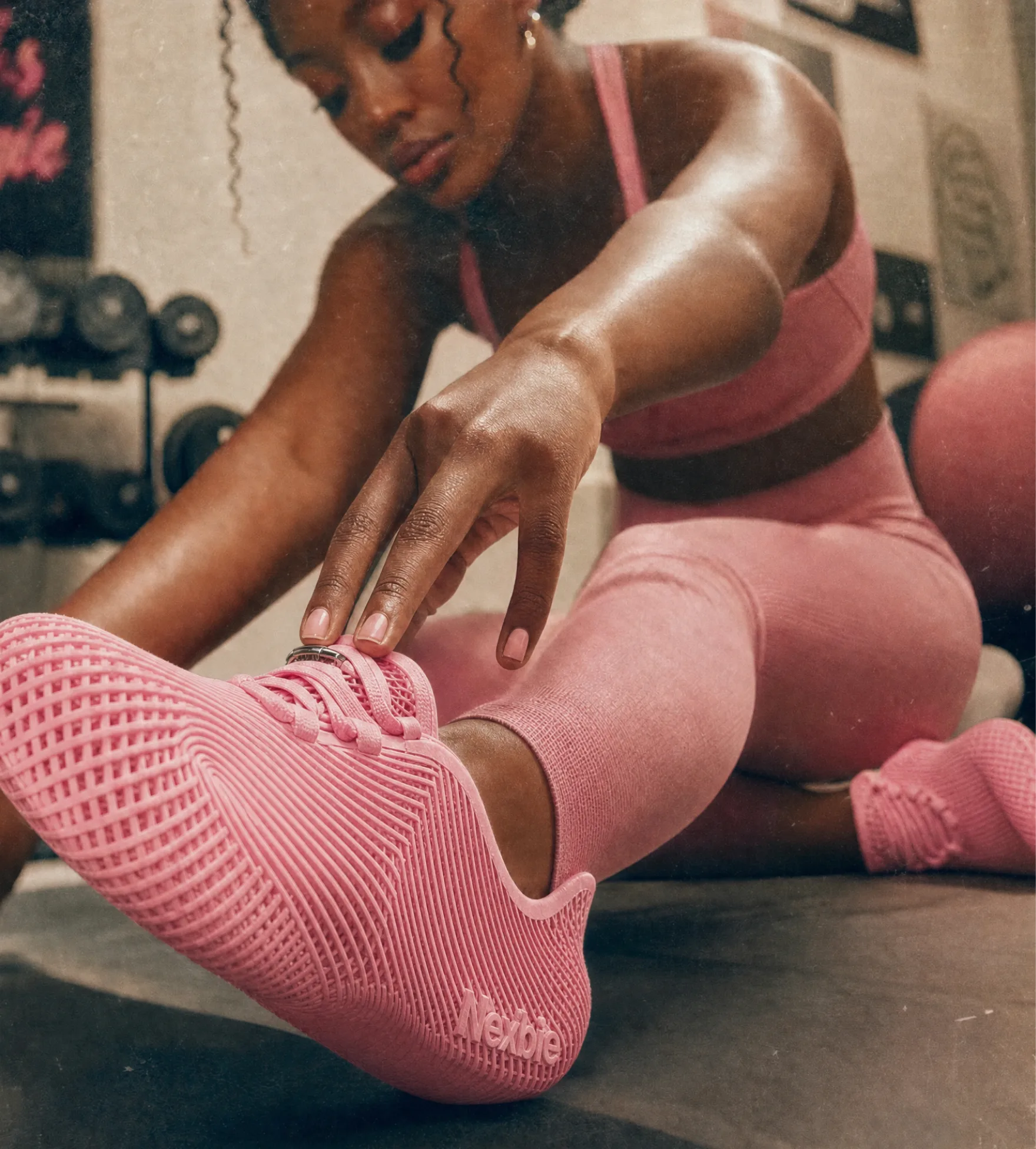 Woman stretching in a gym wearing pink Aeroraise sneakers