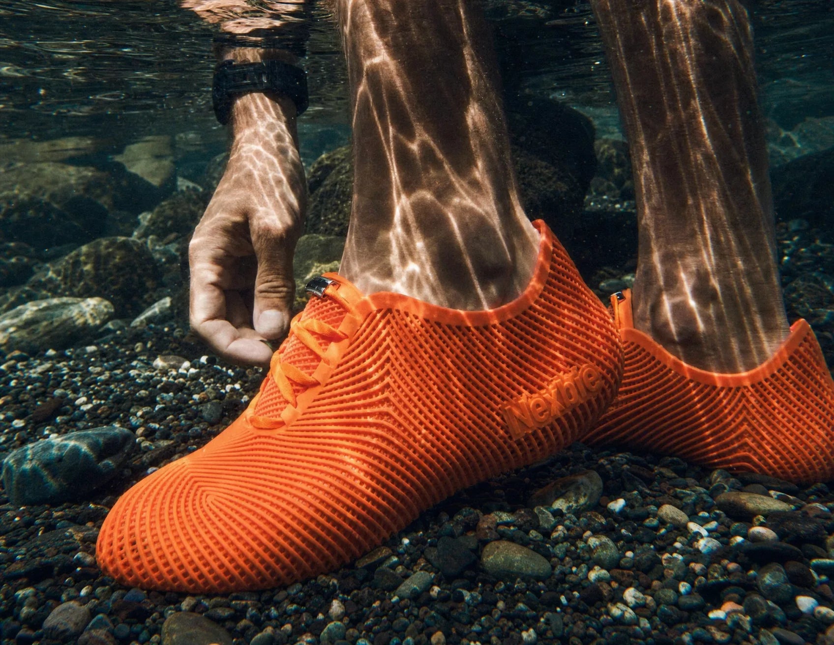 Underwater shot of orange Aeroraise sneakers on a riverbed